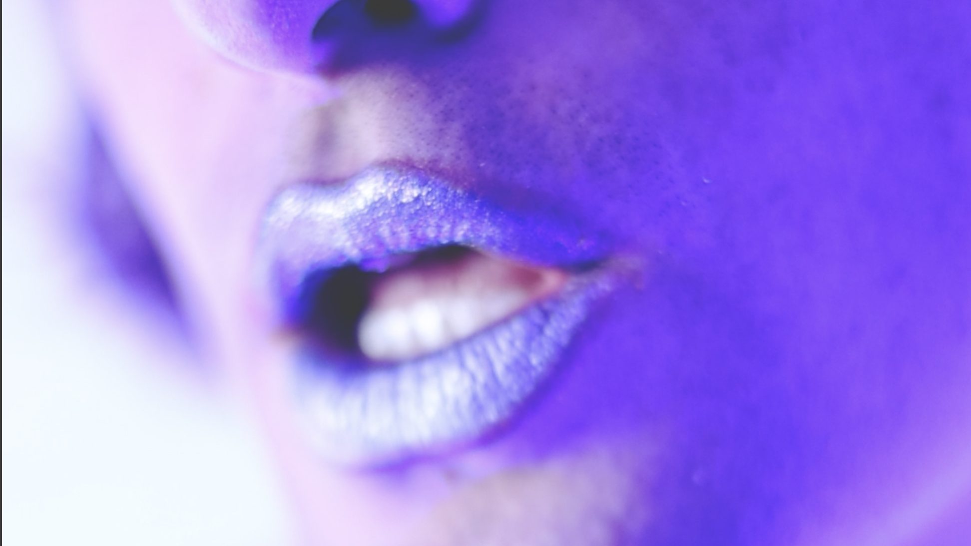 A pair of silver lips on fair, ultraviolet-lit skin